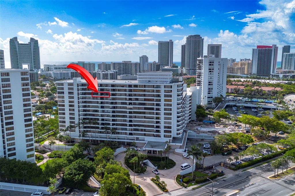 An aerial view of a multi-story residential building with a red arrow pointing to a balcony — 500 THREE ISLANDS BOULEVARD UNIT 1008, HALLANDALE BEACH, FL
