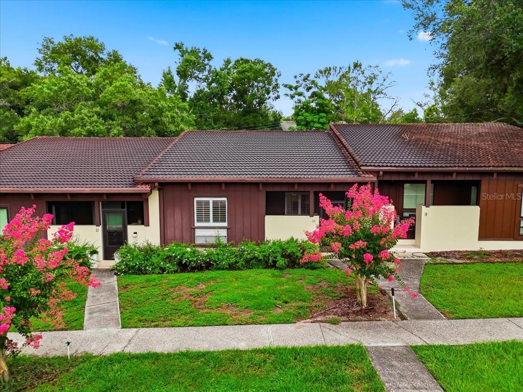 A row of three attached single-story homes with brown siding and dark tiled roofs — 10 EL RECODO UNIT 10, LAKELAND, FL
