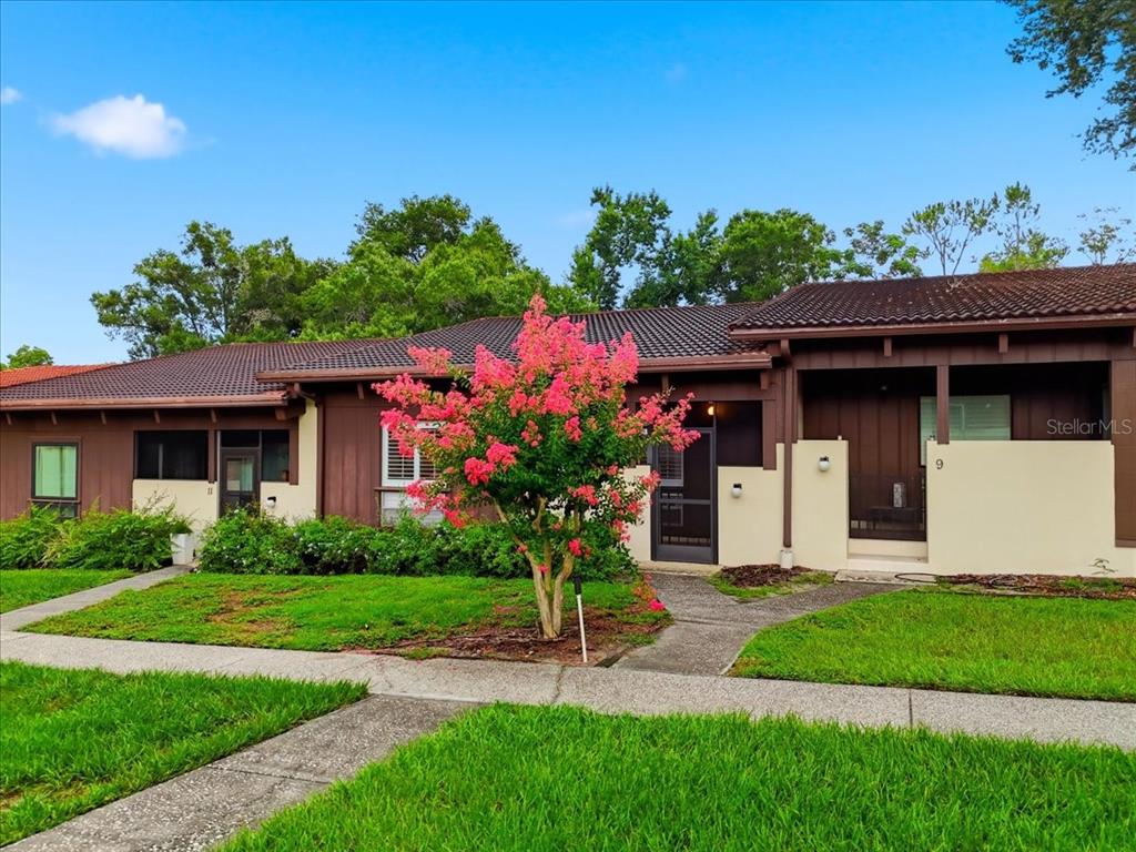 A single-story residential building with brown siding, a tiled roof, and a blooming crape myrtle — 10 EL RECODO UNIT 10, LAKELAND, FL