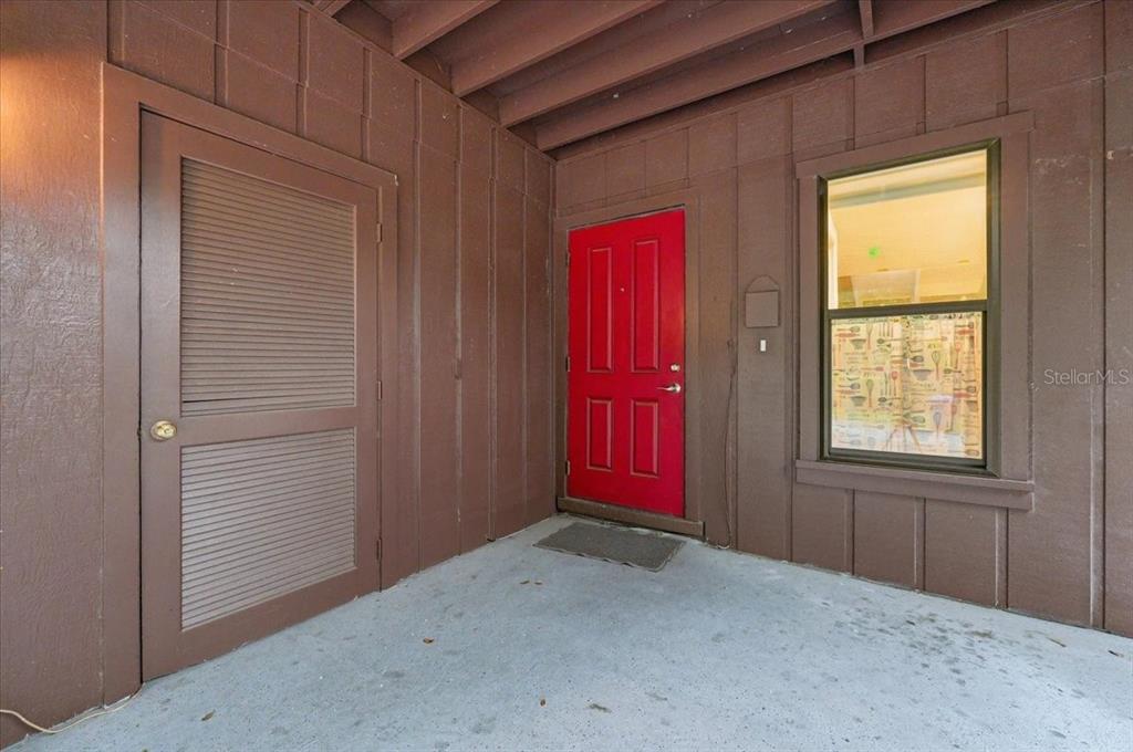 A red front door and a louvered storage closet door on a covered porch — 10 EL RECODO UNIT 10, LAKELAND, FL