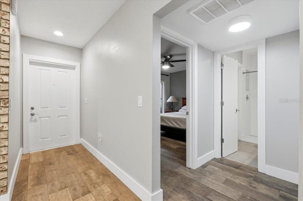 A hallway with wood-look tile flooring leads to a bedroom and a bathroom — 10 EL RECODO UNIT 10, LAKELAND, FL
