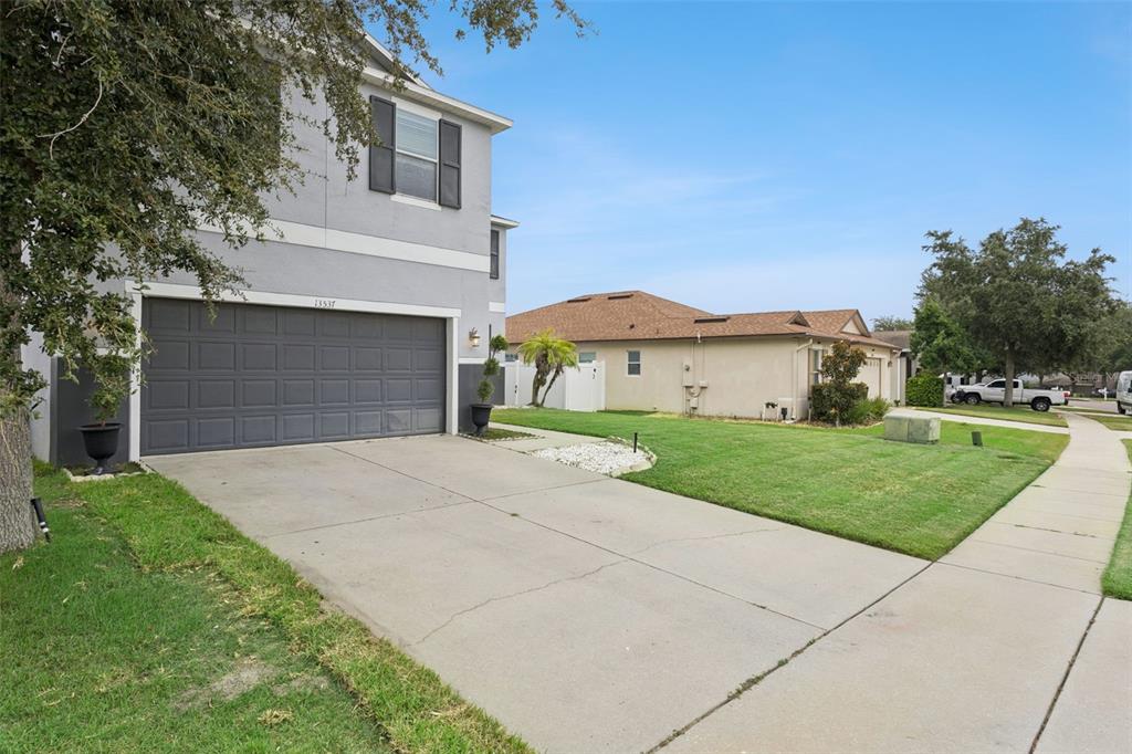 A two-story house with a gray garage and a concrete driveway next to a lawn — 13537 LARANJA STREET, CLERMONT, FL