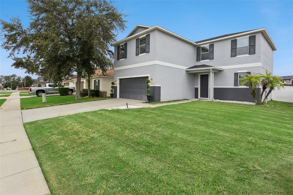 A two-story gray house with a two-car garage and a front lawn under a blue sky — 13537 LARANJA STREET, CLERMONT, FL