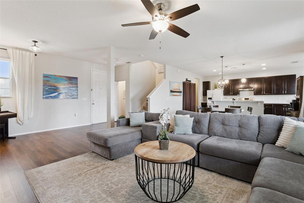 A living room with a gray sectional sofa, round coffee table, and open kitchen — 13537 LARANJA STREET, CLERMONT, FL