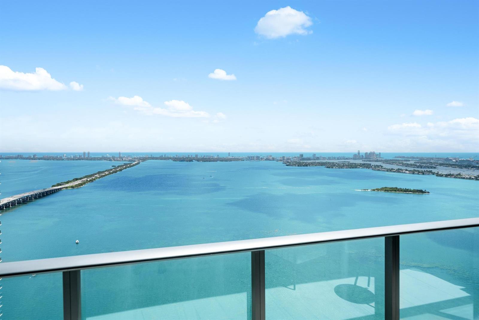 A bright living and dining area features floor-to-ceiling windows with expansive ocean views — 480 NE 31st Street, Miami FL 33137, MIAMI, FL