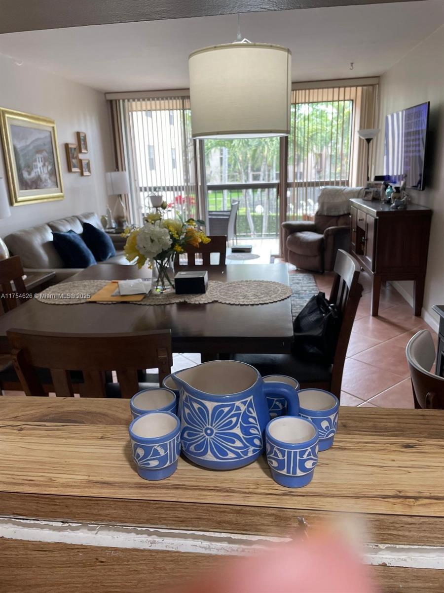 A dining area and living room feature tile floors, a wooden table, and a balcony view — 10985 SW 107th St # 211, Miami FL 33176, MIAMI, FL