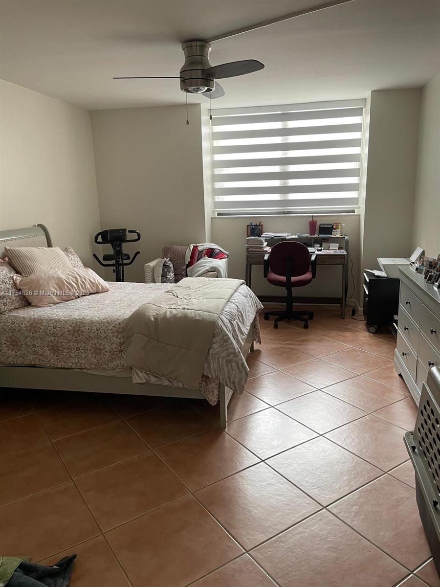 A bedroom features a bed, a desk with a chair, and tile flooring — 10985 SW 107th St # 211, Miami FL 33176, MIAMI, FL