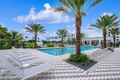 A swimming pool is surrounded by lounge chairs and palm trees on a paved patio — 10985 SW 107th St # 211, Miami FL 33176, MIAMI, FL