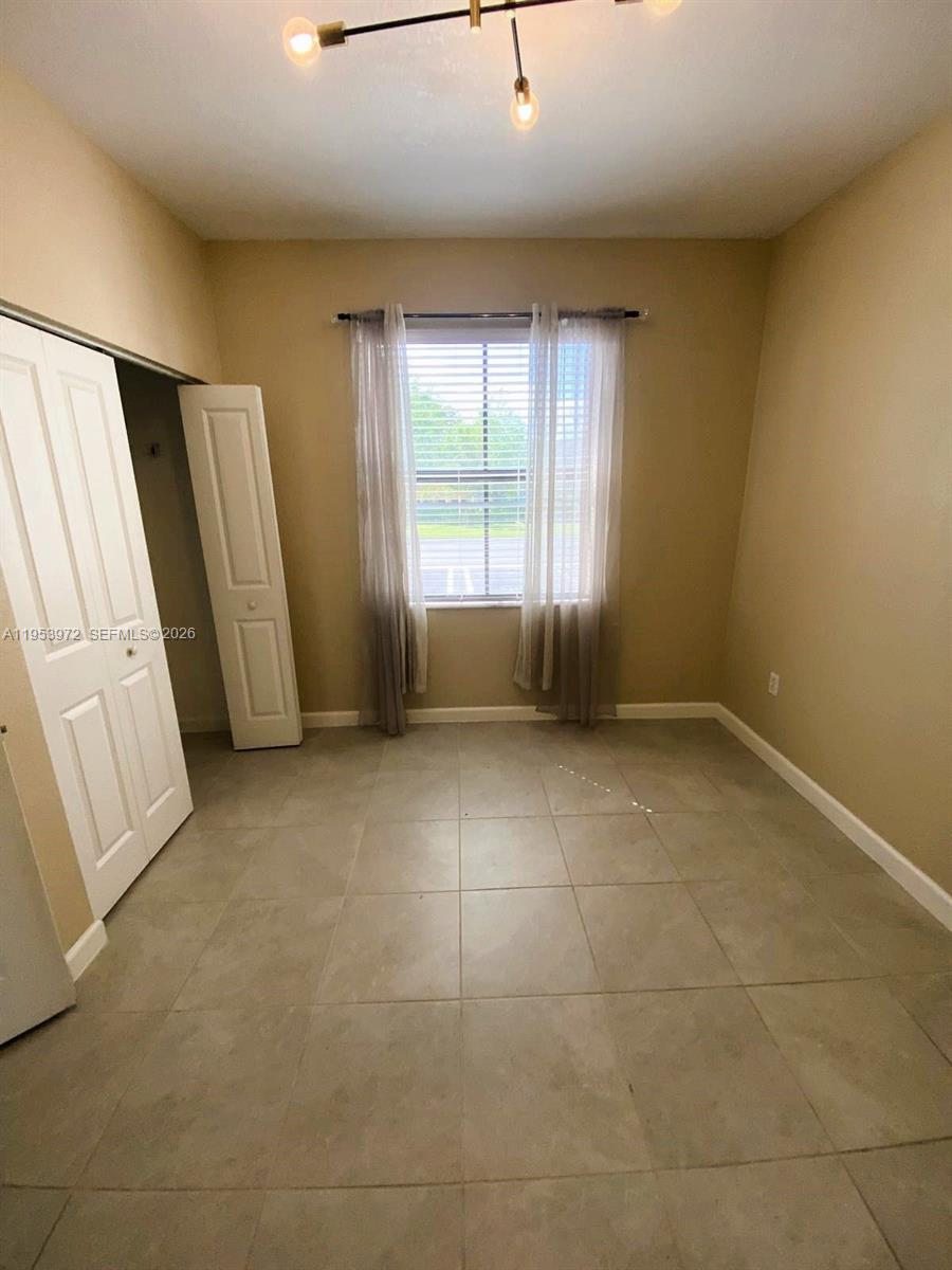 A bedroom features beige walls, tile flooring, a window with curtains, and a closet — 18220 SW 148th Rd, Miami FL 33187, MIAMI, FL