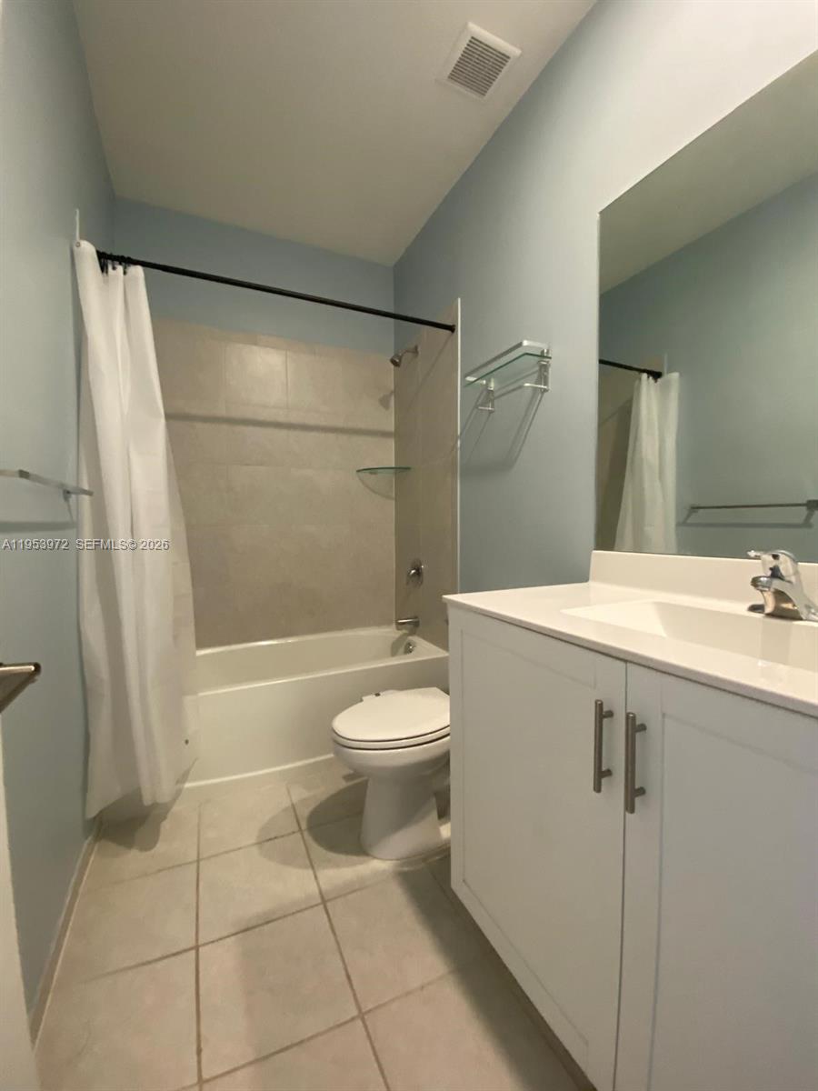 A bathroom features a white vanity, a toilet, and a shower-tub combination with tiled walls — 18220 SW 148th Rd, Miami FL 33187, MIAMI, FL