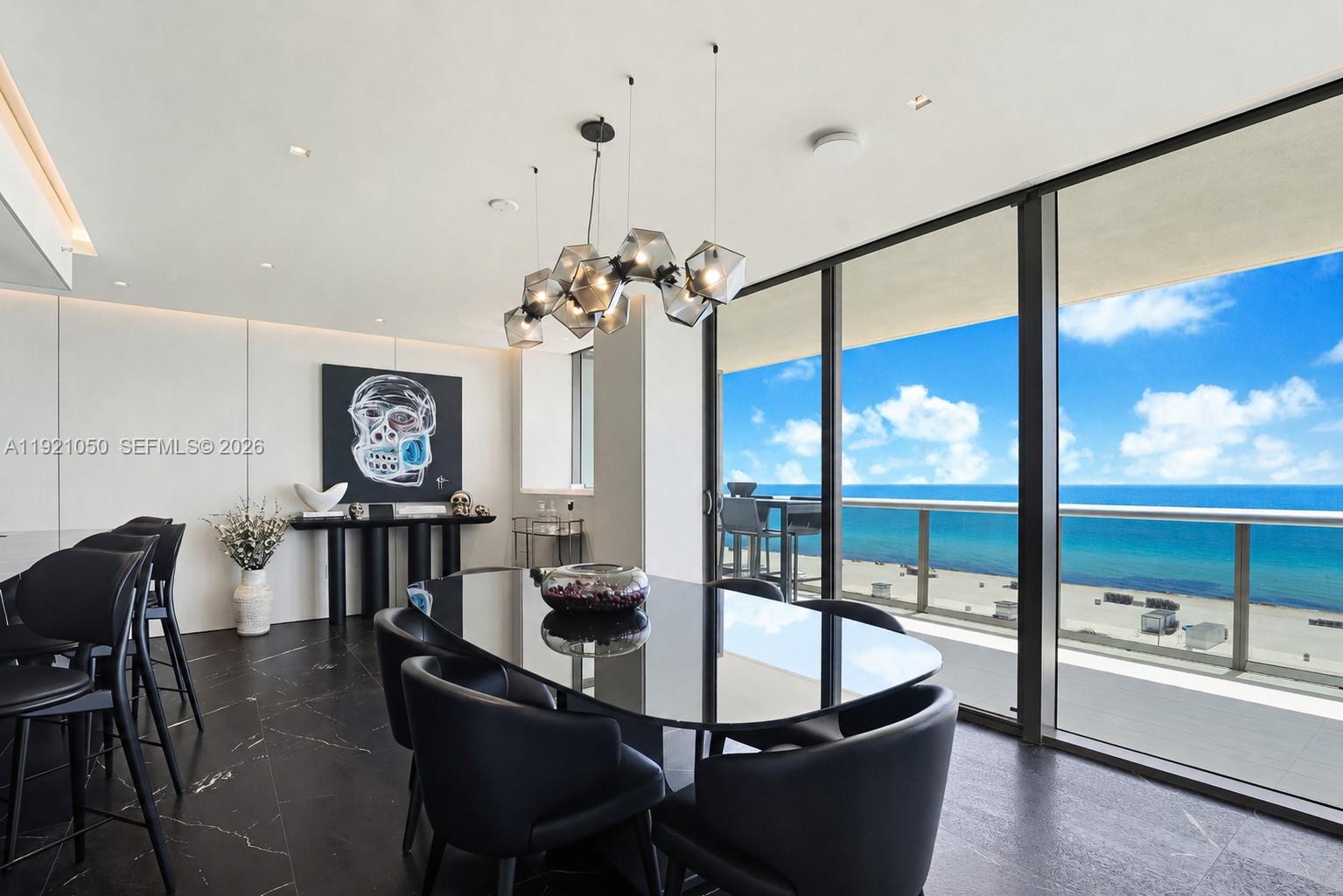 A modern dining room features a black table, matching chairs, and floor-to-ceiling ocean views — 5875 Collins Ave # 902, Miami Beach FL 33140, MIAMI BEACH, FL