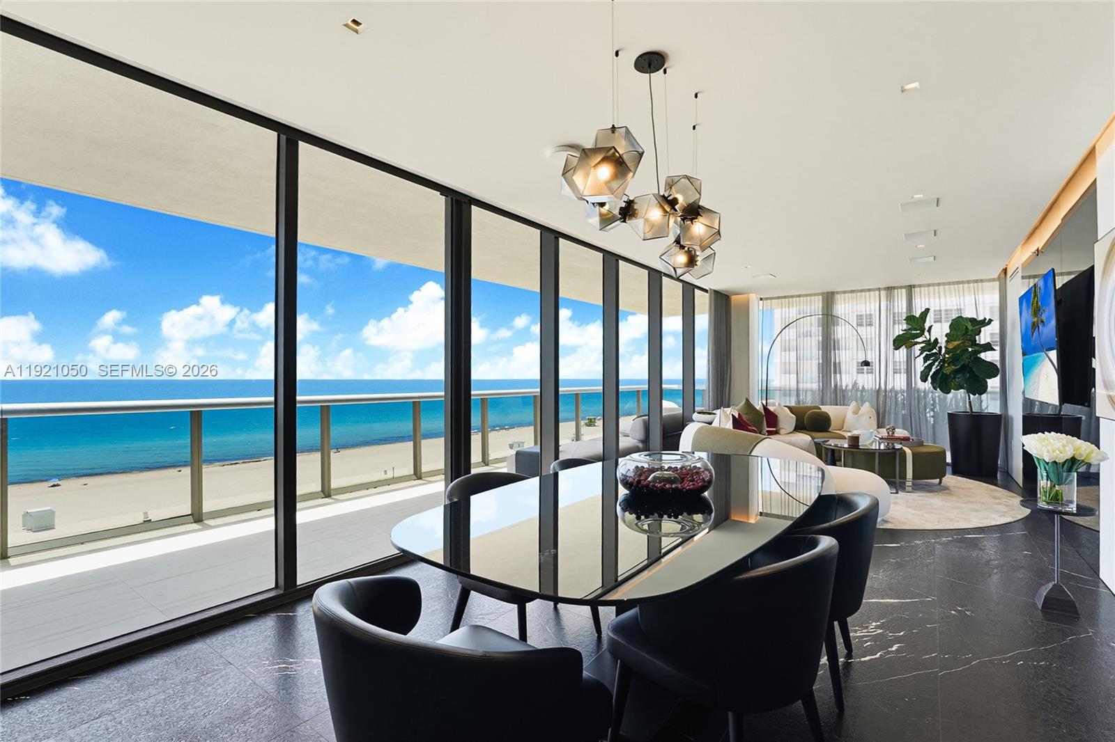 A modern dining area with a glass table overlooks the ocean through floor-to-ceiling windows — 5875 Collins Ave # 902, Miami Beach FL 33140, MIAMI BEACH, FL