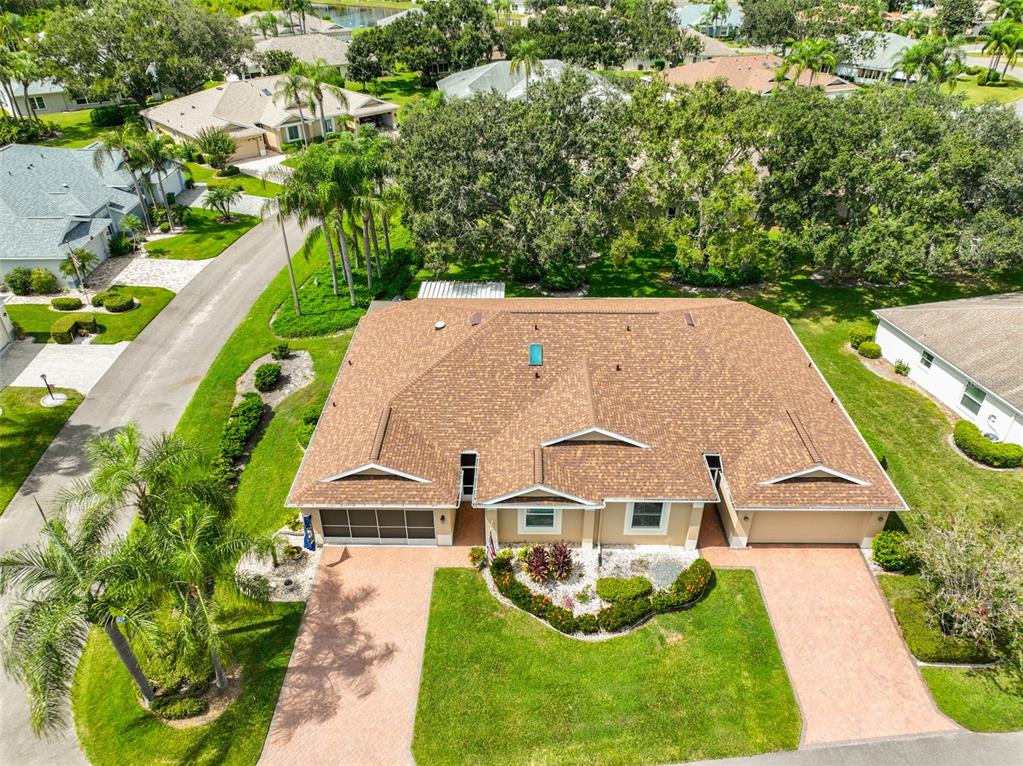 An aerial view shows a tan duplex with a brown shingled roof and two driveways — 751 MCCALLISTER AVENUE, SUN CITY CENTER, FL