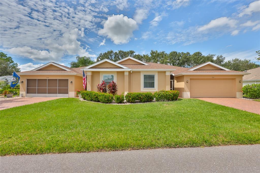 A tan single-story house with two garages, a green lawn, and a paved driveway — 751 MCCALLISTER AVENUE, SUN CITY CENTER, FL