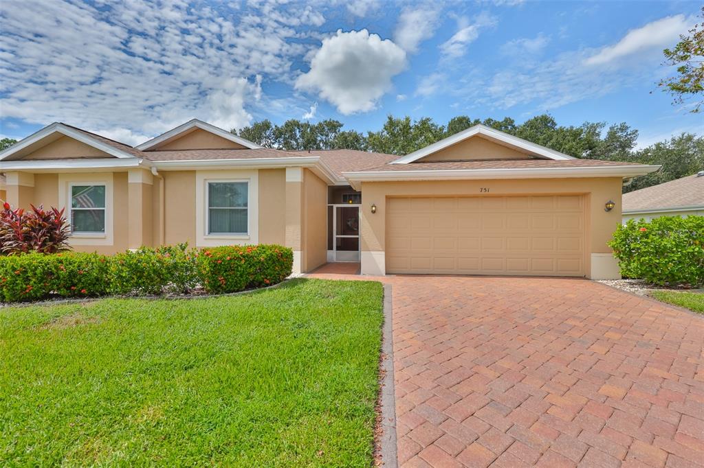 A single-story house with a tan stucco exterior, a brick paver driveway, and a garage — 751 MCCALLISTER AVENUE, SUN CITY CENTER, FL