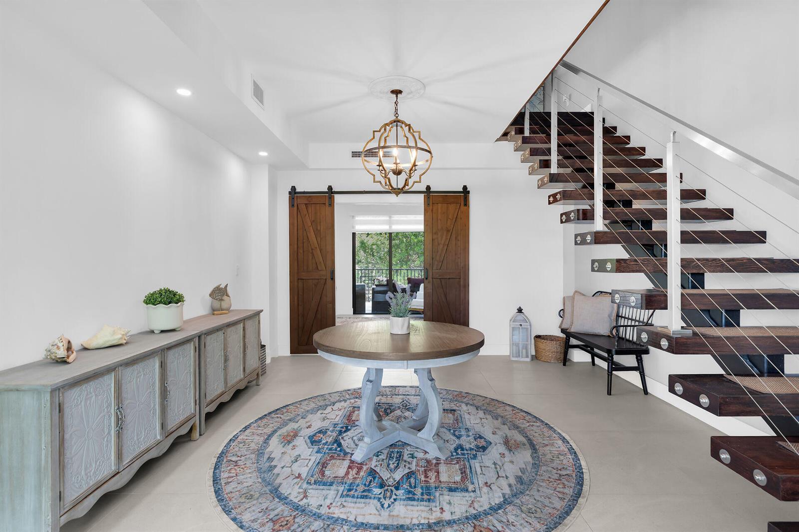 A foyer features a round table, a patterned rug, a wooden sideboard, and a staircase — 239 W Seaview Drive, FL 33050, FL