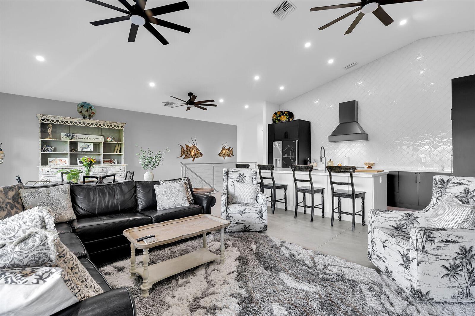 A living room and kitchen area with a black leather sofa, patterned chairs, and island seating — 239 W Seaview Drive, FL 33050, FL