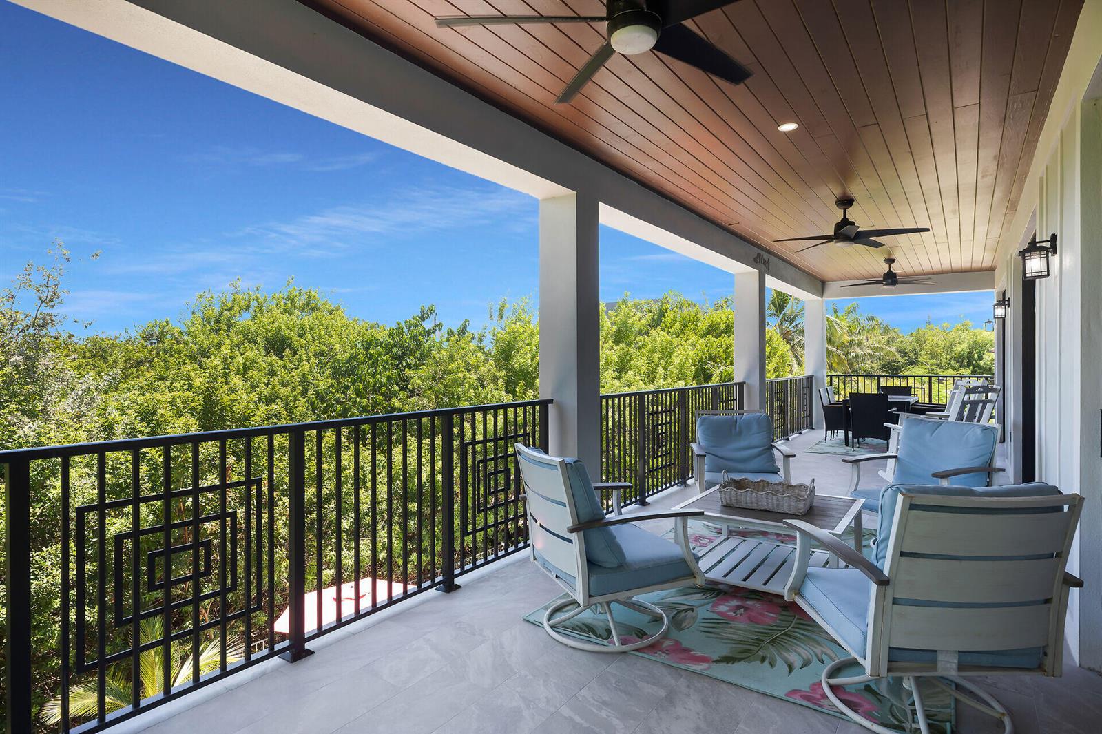 A covered outdoor balcony features a seating area with blue chairs, ceiling fans, and railings — 239 W Seaview Drive, FL 33050, FL