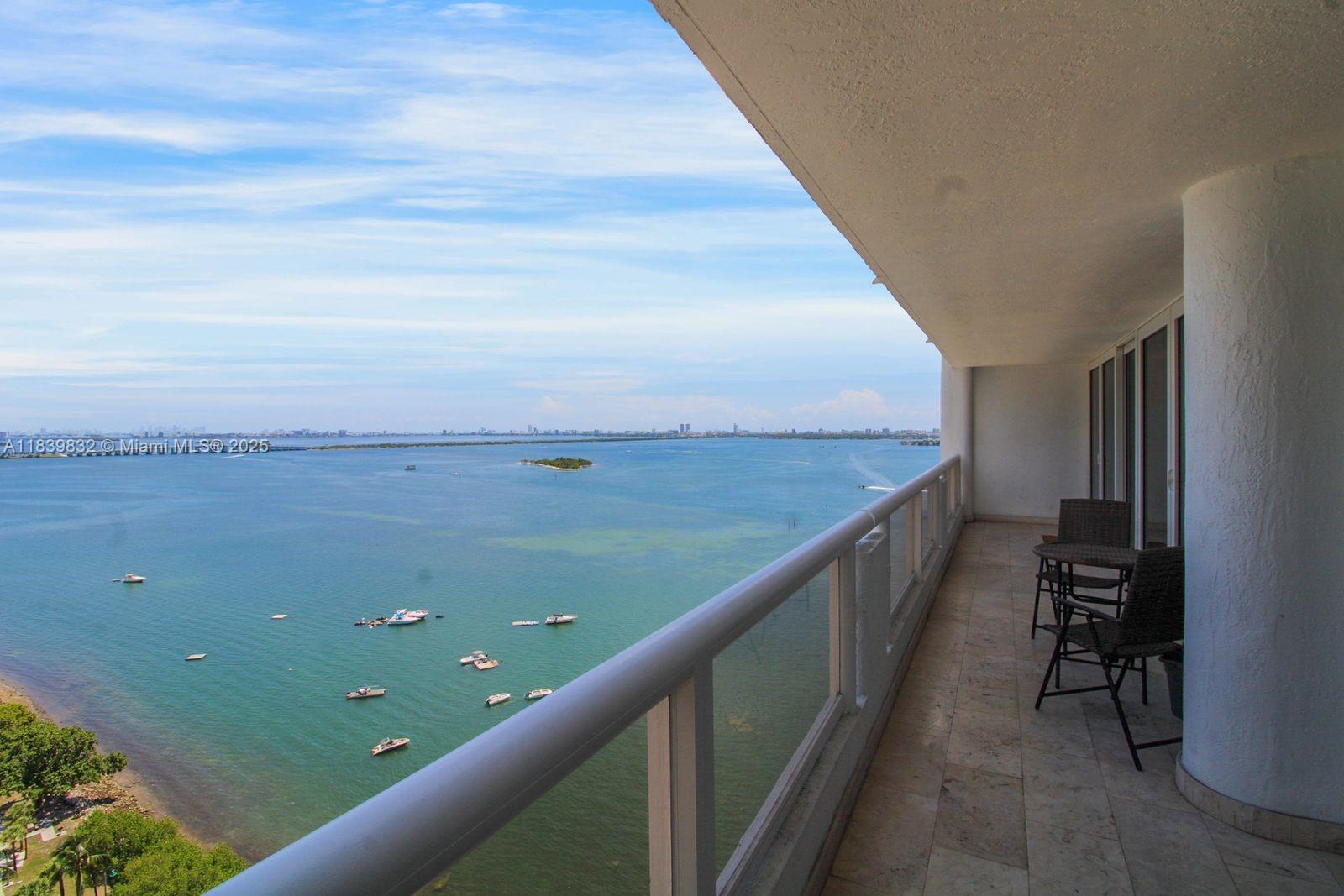 A balcony with tile flooring overlooks a large body of water and a distant city — 1717 N Bayshore Dr # 2635, Miami FL 33132, MIAMI, FL