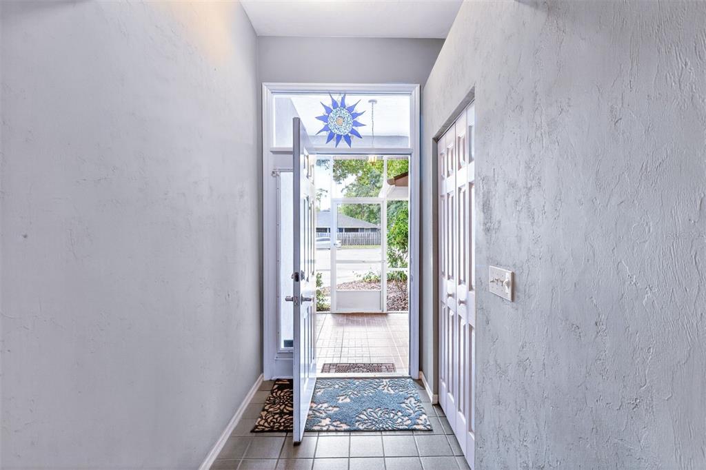 An entryway with light gray walls, tiled flooring, and a door opening to a screened porch — 2305 NW 44TH PLACE, GAINESVILLE, FL
