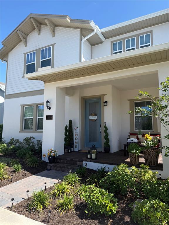 A two-story house features a covered front porch, a blue door, and a stone walkway — 13456 LAXNESS STREET, ORLANDO, FL