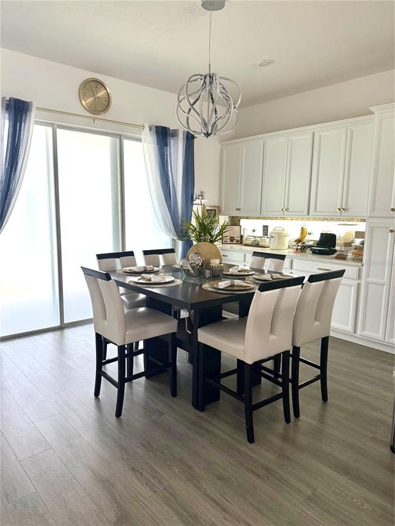 A dining area features a dark wood table, light-colored chairs, and white kitchen cabinetry — 13456 LAXNESS STREET, ORLANDO, FL
