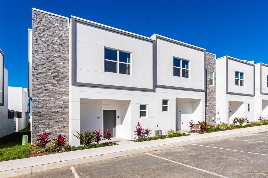 A rectangular swimming pool sits on a patio in front of modern townhome buildings — 277 FAMAGUSTA DRIVE, DAVENPORT, FL