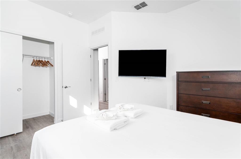 A bedroom features a bed with white linens, two nightstands with lamps, and floor-length curtains — 277 FAMAGUSTA DRIVE, DAVENPORT, FL