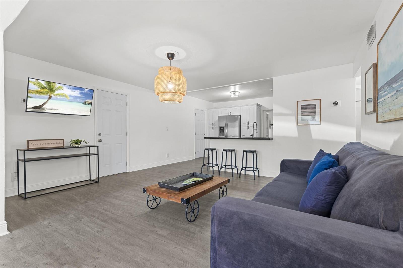 A living room with gray flooring, a dark sofa, a coffee table, and a kitchen — 6375 SW 29th Street, Miami FL 33155, MIAMI, FL