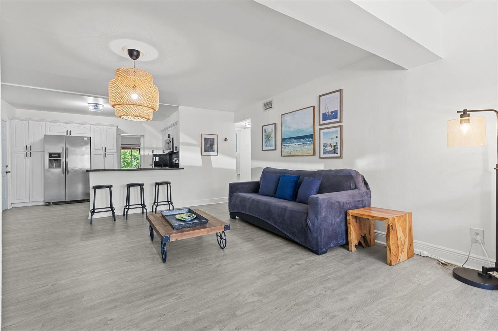 A living room with gray wood-look flooring, a blue sofa, and an open kitchen area — 6375 SW 29th Street, Miami FL 33155, MIAMI, FL
