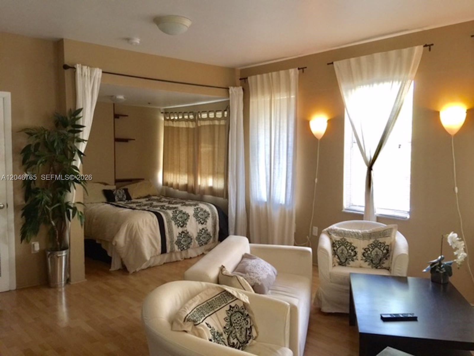 A studio apartment features a bed in an alcove, a living area, and light-colored walls — 802 Euclid Ave # 201, Miami Beach FL 33139, MIAMI BEACH, FL