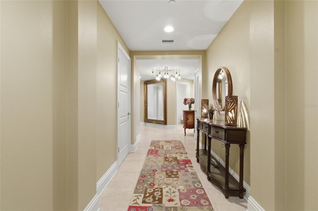 A hallway with tile flooring, a patterned runner rug, and a wooden console table — 11 BAYMONT STREET UNIT 608, CLEARWATER BEACH, FL