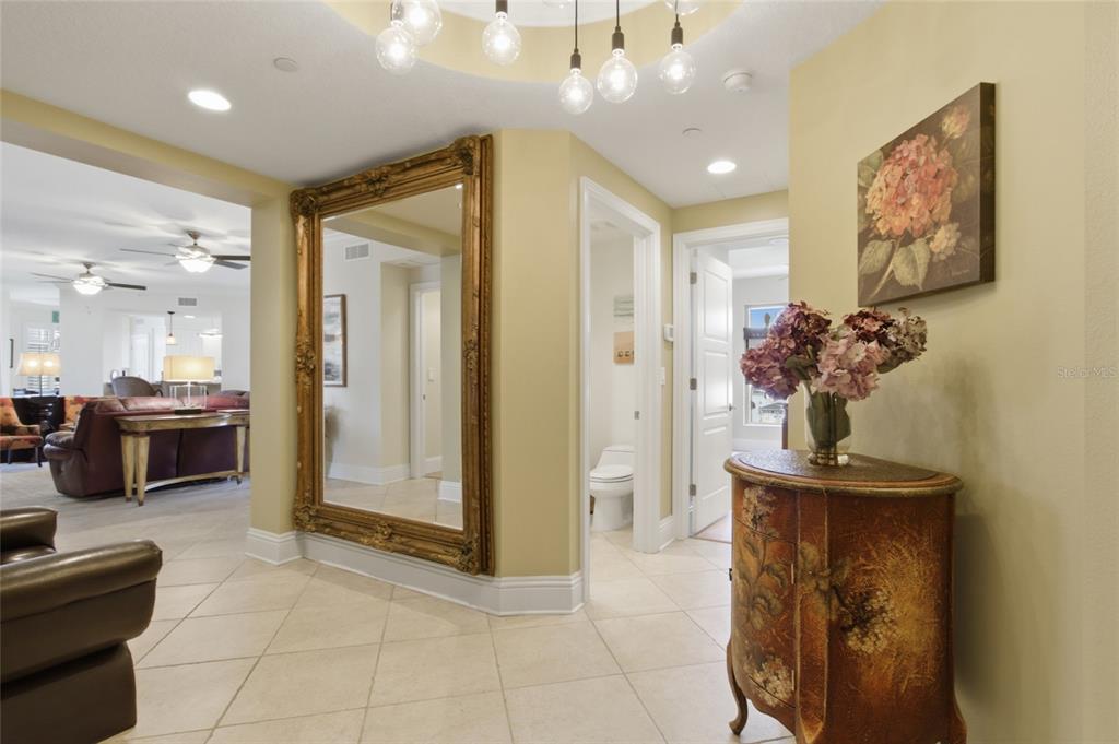 A foyer features a large gold-framed mirror, a floral chest, and a modern light fixture — 11 BAYMONT STREET UNIT 608, CLEARWATER BEACH, FL