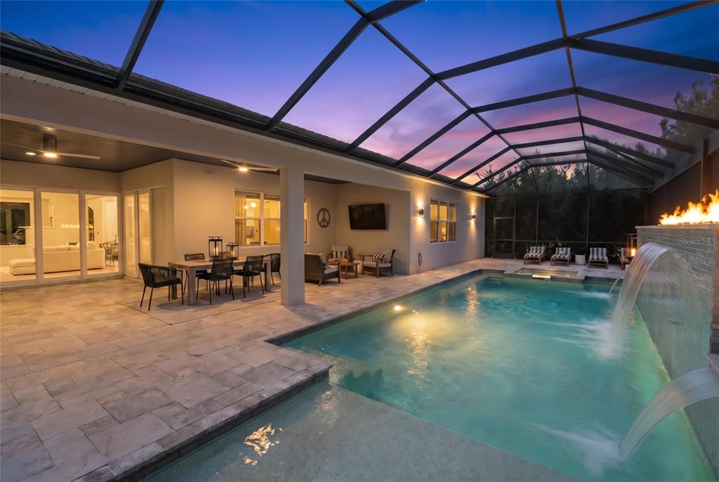 A screened-in pool area features a fire feature, multiple waterfalls, and stone patio flooring — 12215 PORTSMOUTH TERRACE, BRADENTON, FL