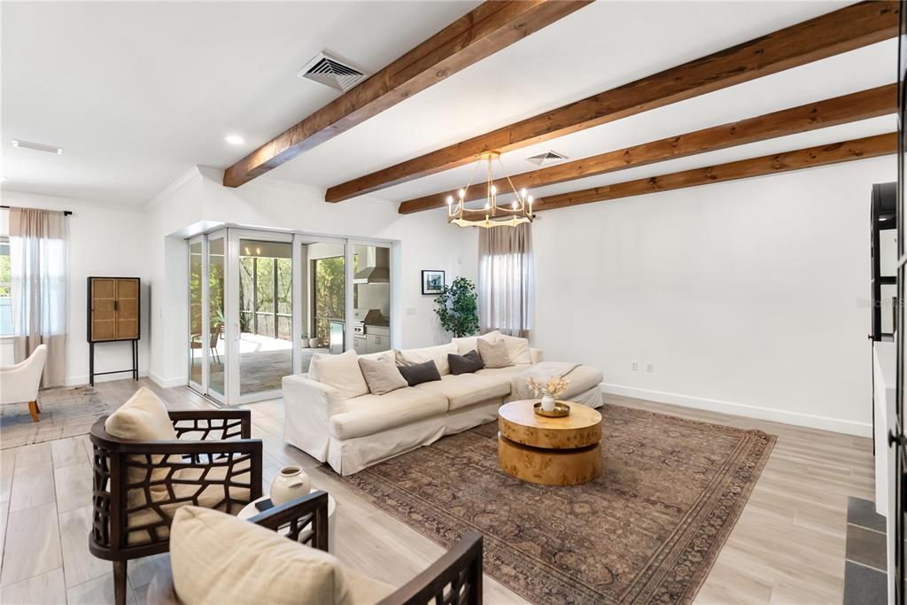 A modern open-concept kitchen features a dark island, white cabinetry, and wood-look tile flooring — 12215 PORTSMOUTH TERRACE, BRADENTON, FL