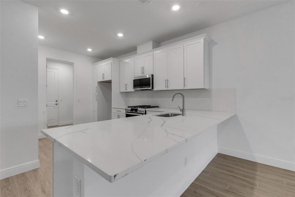 A modern kitchen features white cabinets, marble-look countertops, and a breakfast bar island — 18181 CHERISHED LOOP, BRADENTON, FL