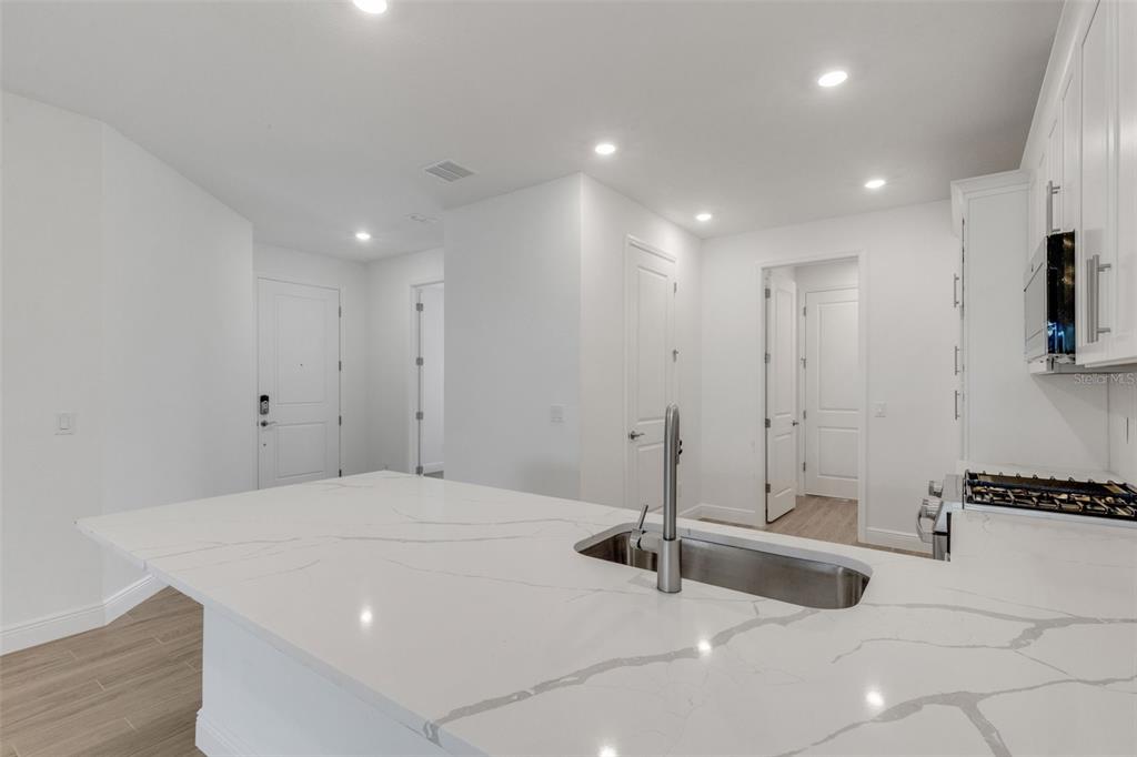 A modern kitchen features a white quartz island with a sink and white cabinetry — 18181 CHERISHED LOOP, BRADENTON, FL