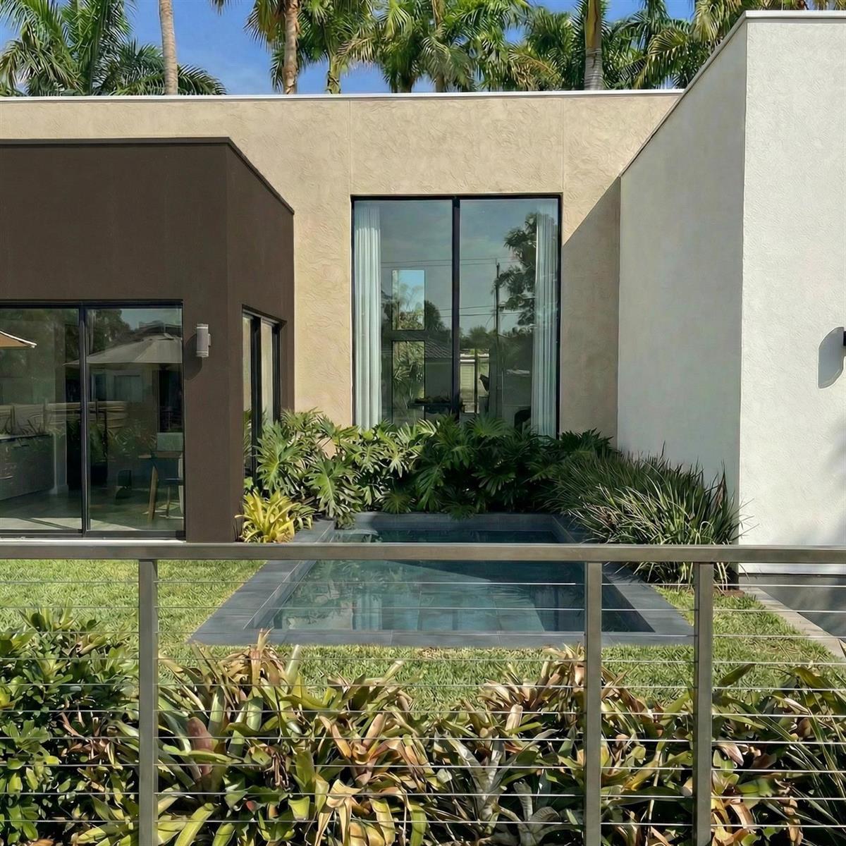 A modern home exterior features a small rectangular pool nestled between dark and light walls — 2500 NE 18th Avenue, Wilton Manors FL 33305, WILTON MANORS, FL