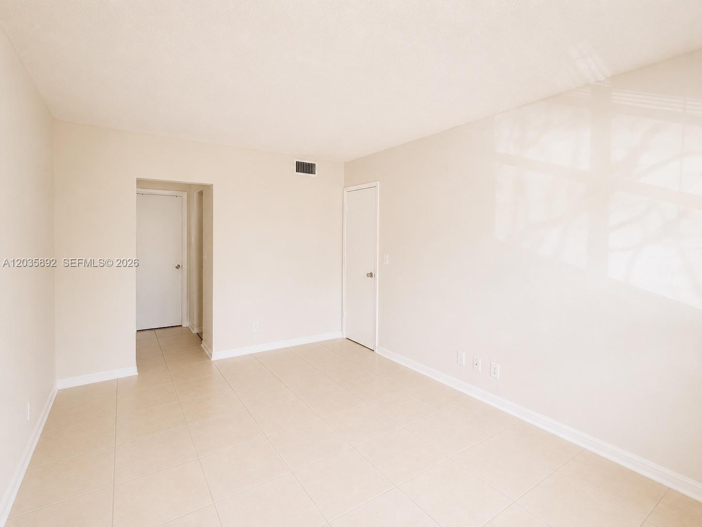 An empty room features beige tile flooring, white walls, and two closed white doors — 280 S Cypress Rd # 310, Pompano Beach FL 33060, POMPANO BEACH, FL