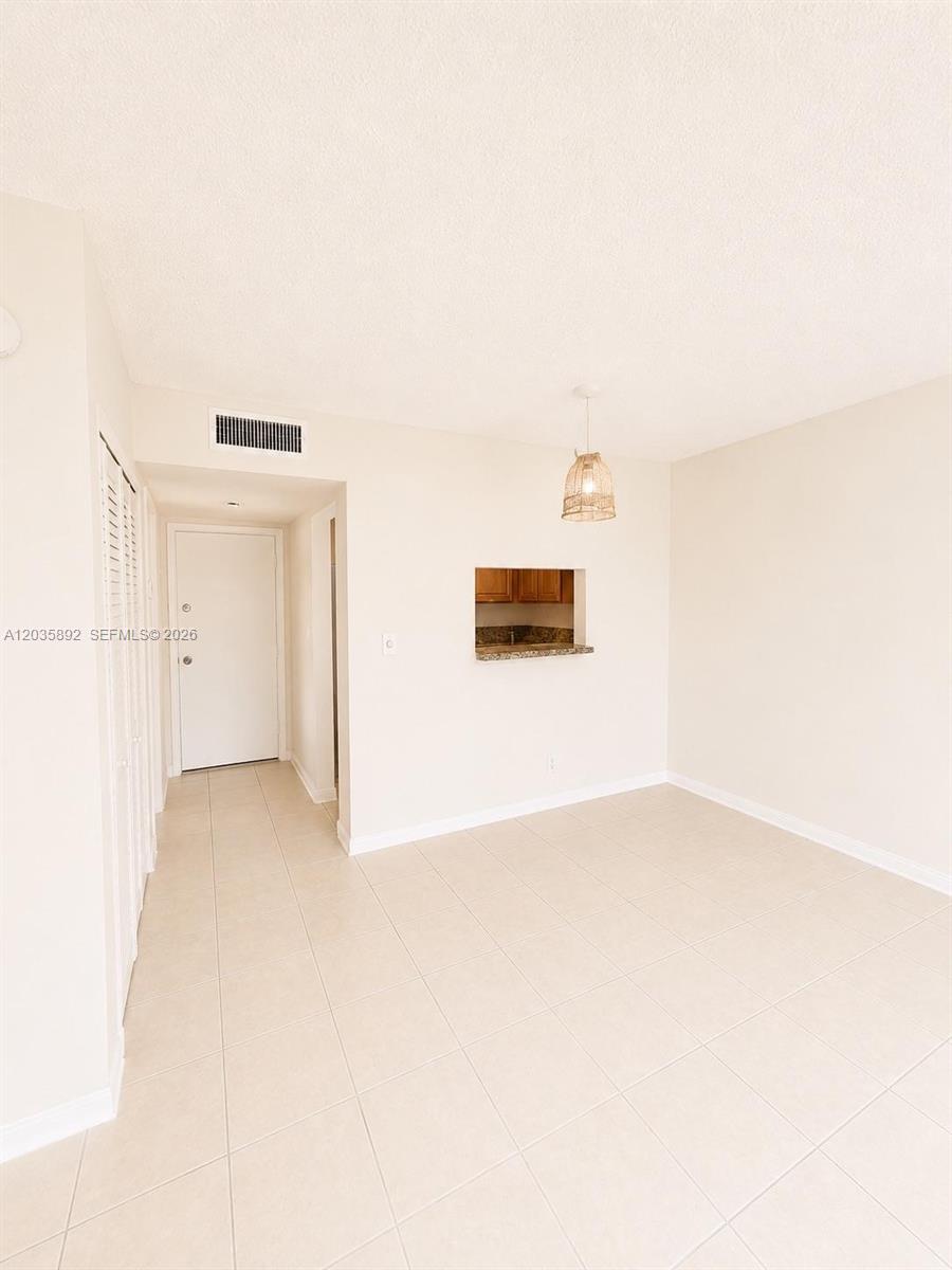 This room features beige tile flooring, a pass-through window to the kitchen, and lighting — 280 S Cypress Rd # 310, Pompano Beach FL 33060, POMPANO BEACH, FL