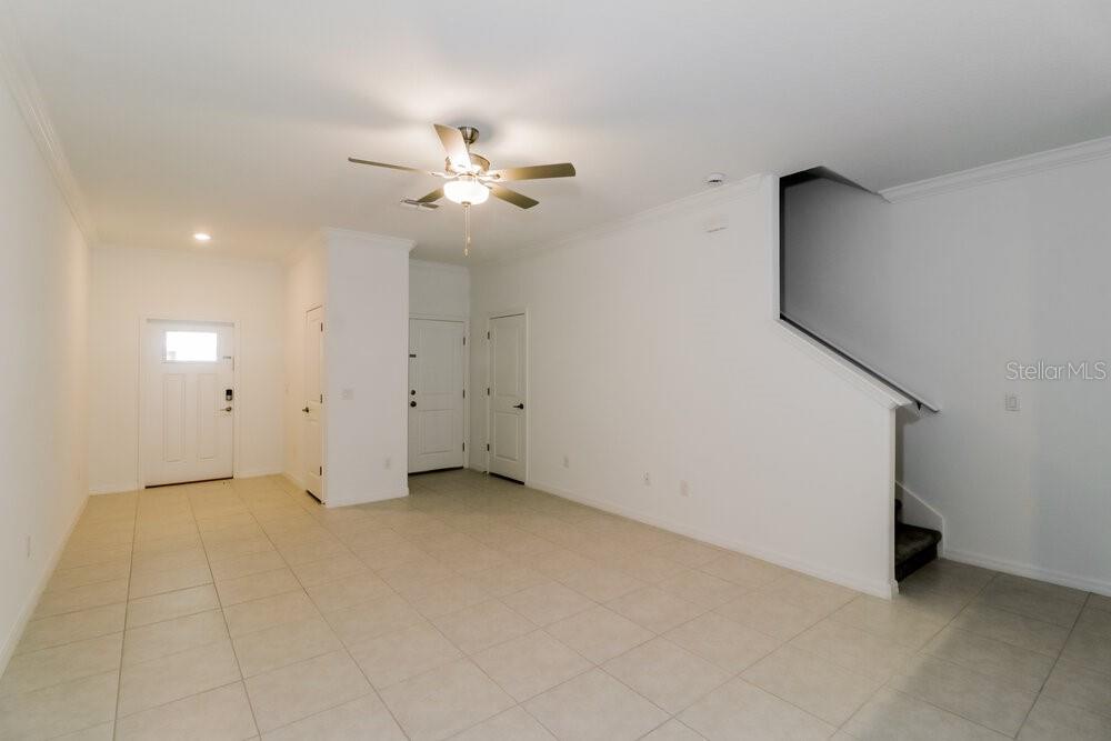 An empty room with white walls, tiled floors, a ceiling fan, and a staircase — 2145 GREAT SAPPHIRE LANE, LUTZ, FL