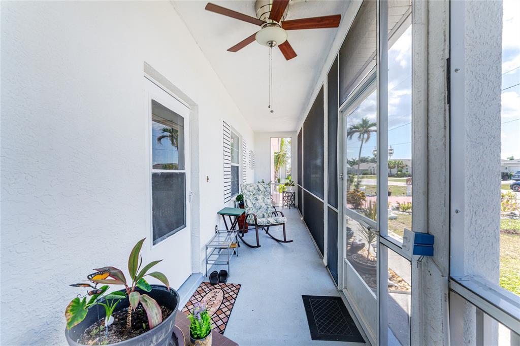 A screened-in porch features a ceiling fan, a rocking chair, and a white door — 25324 ALICANTE DRIVE, PUNTA GORDA, FL