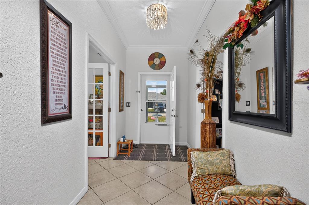 An entryway features tile flooring, a glass-paneled front door, a chandelier, and a decorative mirror — 25324 ALICANTE DRIVE, PUNTA GORDA, FL