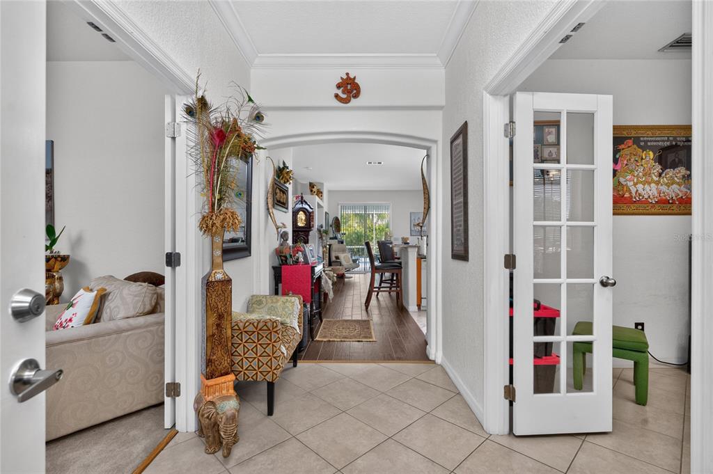 A tiled entryway leads through an arched doorway into a living area with wood floors — 25324 ALICANTE DRIVE, PUNTA GORDA, FL