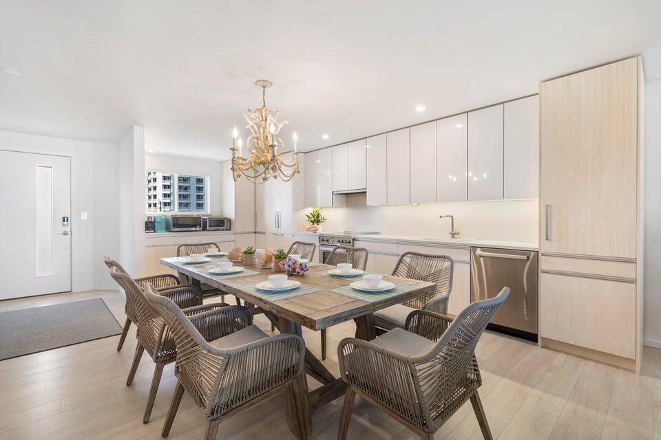 A dining area with a wooden table and wicker chairs sits before a modern kitchen — 350 S Beach Road # 305, Jupiter FL 33469, JUPITER, FL