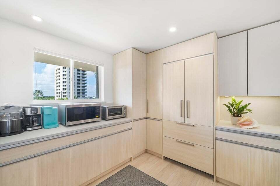 A kitchen features light wood cabinetry, a built-in refrigerator, and a window with a view — 350 S Beach Road # 305, Jupiter FL 33469, JUPITER, FL