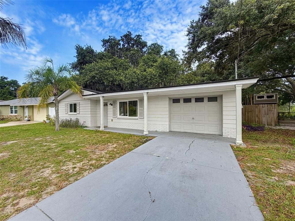A single-story white house with a garage, a concrete driveway, and a front porch — 6845 MEDLAR DRIVE, NEW PORT RICHEY, FL