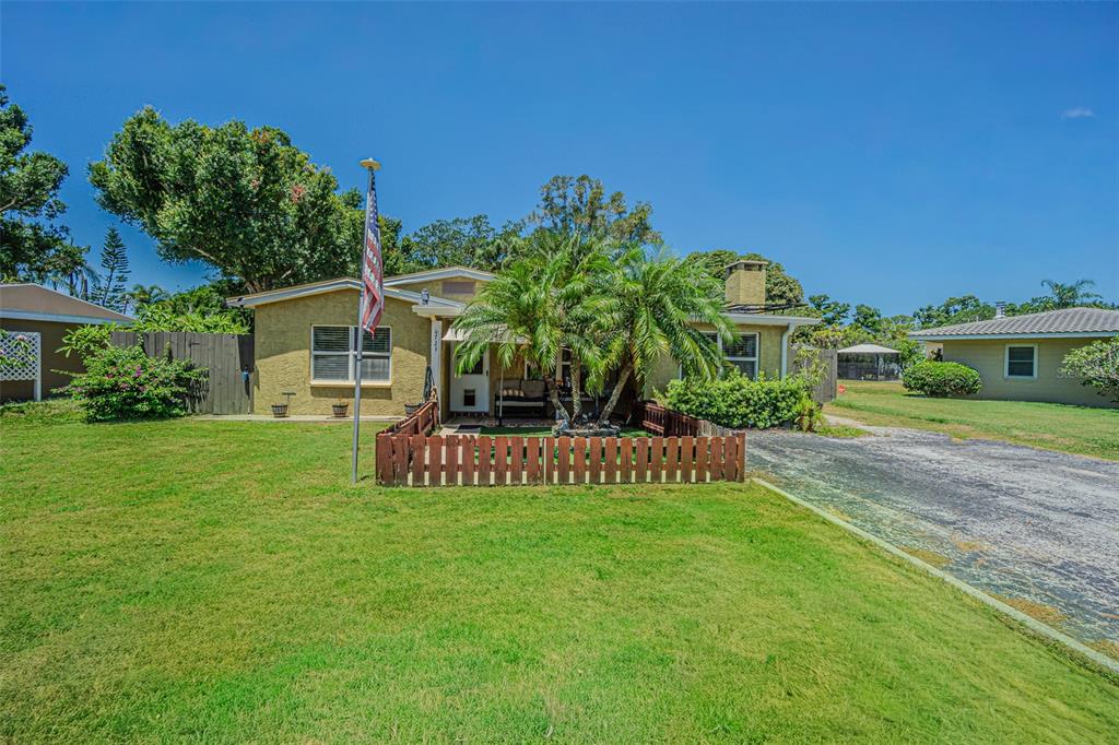 A single-story house with a yellow stucco exterior, a small front fence, and palm trees — 721 OLEANDER WAY S, SOUTH PASADENA, FL