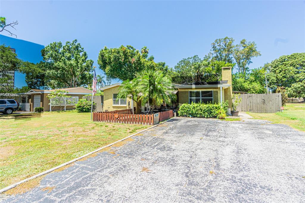 A single-story house with a paved driveway, a small fenced yard, and mature trees — 721 OLEANDER WAY S, SOUTH PASADENA, FL