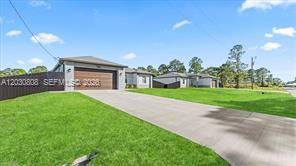 A concrete driveway leads to the garage of a single-story house with a grassy lawn — 759 SILVERSTAR AVE S, Lehigh Acres FL 33974, LEHIGH ACRES, FL